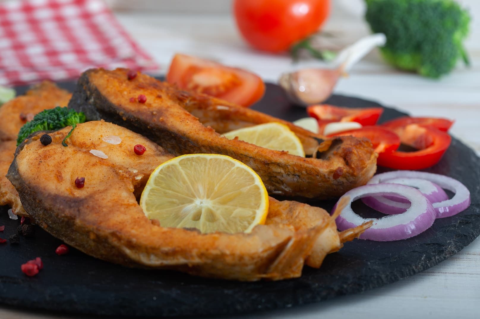 Fried carp fish slices on a black plate.  Fried golden crust fish fillets with  lemon and vegetables.