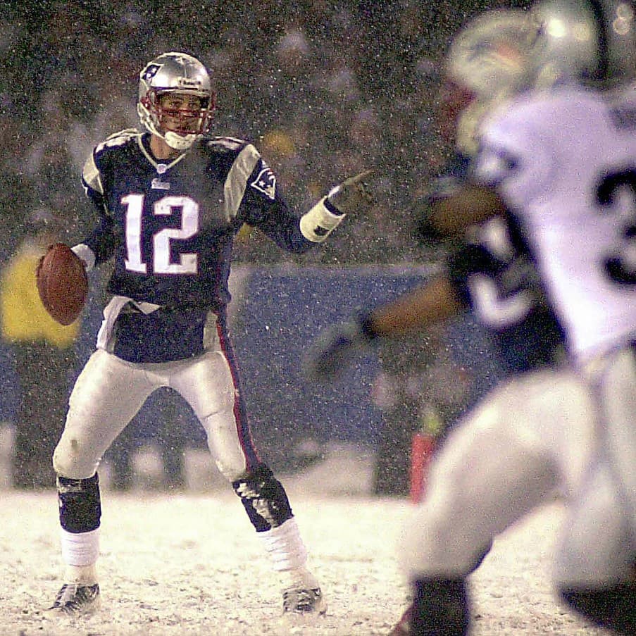 Quarterback Tom Brady (L) of the New England Patriots feels the pressure from the Oakland Raiders defense in the third quarter in their AFC playoff game 19 January 2002 at Foxboro Stadium in Foxboro, Massachusetts. AFP PHOTO/JOHN MOTTERN (Photo by JOHN MOTTERN / AFP)