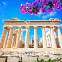 facade of Parthenon temple over bright blue sky background with flowers, Acropolis hill, Athens Greece