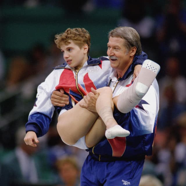 ATLANTA - JULY 23:  Coach Bela Karolyi carries Kerri Strug of the United States after she injured herself on her first attempt while competing in the vault, part of the Womens Team Gymnastics competition at the 1996 Olympic Games on July 23, 1996 at the Georgia Dome in Atlanta, Georgia.  (Photo by Mike Powell/Getty Images)