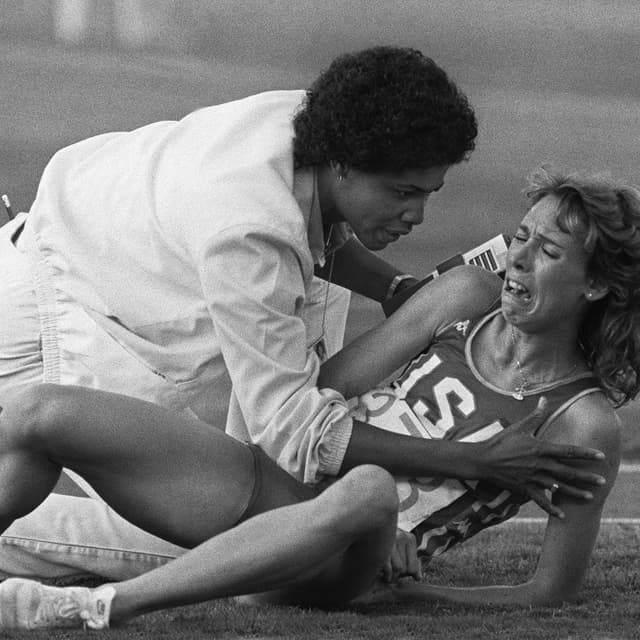 Mary Decker of the USA, comforted by a track official, cries out in frustration after falling down during the women's 3000m final at the Olympic games 11 August 1984 in Los Angeles (B&amp;W only).   AFP PHOTO JEAN-CLAUDE DELMAS (Photo by JEAN-CLAUDE DELMAS / AFP)