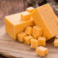 Portion of Cheddar (detailed close-up shot) on vintage wooden background