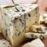 Blue cheese and rosemary sprigs on wooden cutting board