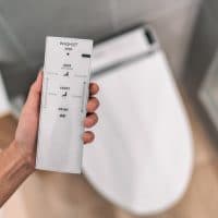 Smart japanese bidet automated toilet washlet with remote for easing cleaning rinsing with water without using toilet paper. at home bathroom modern lifestyle.