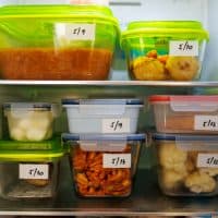 Food leftovers packaged in boxes inside a home fridge with dates written on.