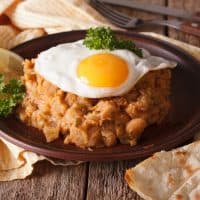 Arabic ful medames with a fried egg and bread close-up on the table. horizontal