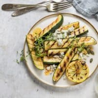 Grilled zucchini and feta cheese salads with lemon dressing on a plate high angle view on table