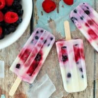 Group of homemade mixed berry yogurt popsicles on a rustic wood background