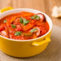 Delicious letcho with fresh vegetables, served in a yellow pot with the fresh bun.