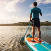 Unrecognizable young Caucasian man, paddleboarding with standup paddleboard on a lake
