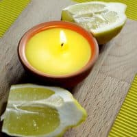Citronella candle lit and lemon fruit on a table, close-up