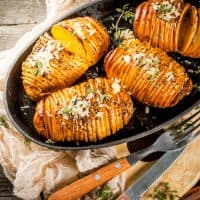 American traditional home cooking. The vegan diet. Homemade Hasselback Potato with Fresh Herbs and cheese. On old wooden table, copy space