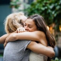 A young couple lovingly embrace each other during a meetup and barbecue with friends.