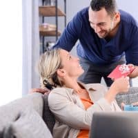 handsome man offering surprise present invitation in envelope gift to his young woman valentine girlfriend