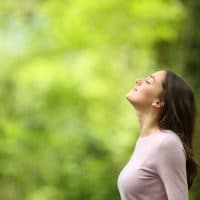 Profile of a relaxed woman breathing fresh air in a green forest