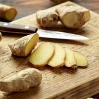 Fresh slice of Ginger on wooden chopping board. healthy food.