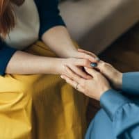 Two women sitting in armchairs and talking. Woman psychologist talking to patient woman. Coach giving hands to smiling woman. Therapist's gestures. Female talking in coworking office