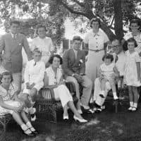 A portrait of the Kennedy family as they sit in the shade of some trees, Hyannis, Massachussetts, 1930s. Seated from left are: Patricia Kennedy (1926 - 2006), Robert Kennedy (1925 - 1968), Rose Kennedy (1890 - 1995), John F Kennedy (1917 - 1963), Joseph P Kennedy Sr (1888 - 1969) with Edward Kennedy on his lap; standing from left are: Joseph P Kennedy Jr (1915 - 1944), Kathleen Kennedy (1920 - 1948), Rosemary Kennedy (1918 - 2005), Eunice Kennedy (rear, in polka dots), and Jean Kennedy. (Photo by Bachrach/Getty Images)