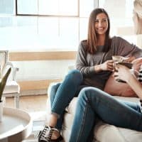 Shot of two women having coffee and chatting while sitting in a living room