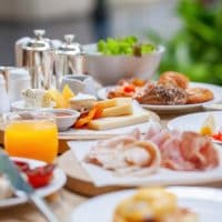 Table full of various fresh food in luxury modern restaurant. Delicious dishes, cold cuts, salmon, omelette, pastries, juices, cheese. Delicious and lavish breakfast or morning meal in high-end hotel