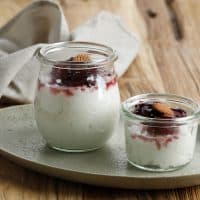Danish Creamy Rice Pudding (Risalamande), Sweet Dessert Served with Warm Cherry Sauce for Christmas Dinner. Served on Jar, Above Wooden Table