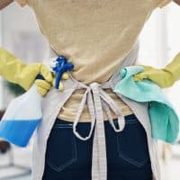 Shot of an unrecognisable woman using rubber gloves and disinfectant to clean her home