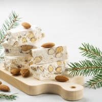 Torrone - soft italian nougat with almonds. Winter decoration. White background.