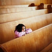 Girl sitting at pews in church.