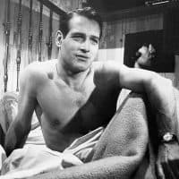 Portrait of actor, Paul Newman, sitting up in bed with no shirt on. Undated photo circa 1950s.