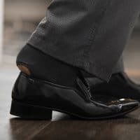 Feet of businessman in shoes with holey sock