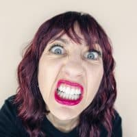 A funny fisheye photo of a 50 year old woman in rage showing her teeth.