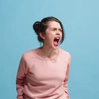 Screaming, hate, rage. Crying emotional angry woman screaming on blue studio background. Emotional, young face. Female half-length portrait. Human emotions, facial expression concept. Trendy colors