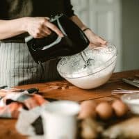 Young woman in kitchen using mixer for wiped cream