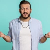 What Why. Sincere irritated lebanese man raising hands in indignant expression asking reason of failure demonstrating disbelief irritation by trouble. Handsome confused arabian guy on blue background