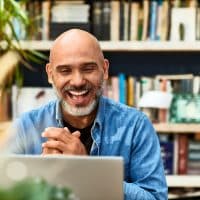 Cheerful handsome mature man at home speaking on video call using laptop, happiness, carefree, relaxation, communication