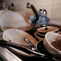 A pile of unwashed dishes stacked in a kitchen sink