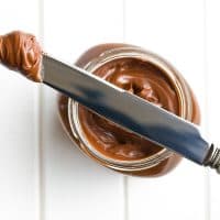 chocolate spread with knife on white table