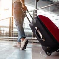 Traveler with suitcase in airport concept.Young girl walking with carrying luggage and passenger for tour travel booking ticket flight at international vacation time in holiday rest and relaxation.