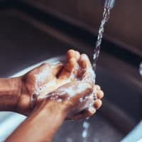 Cropped shot of an unrecognizable man washing his hands in the kitchen sink at home