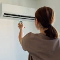 Woman turning on air conditioner with remote