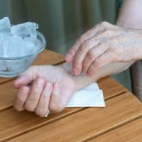 Senior woman holds ice cube on her wrist. How to stay cool in hot weather. Beat the heat. No face, only hands. Close up.