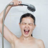 Portrait of a young woman in bathroom screaming in shower