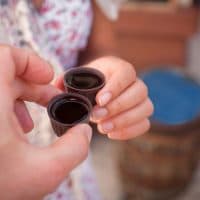 Ginja de Obidos, traditional cherry liquor of Portugal,  in the hands of tourists, close-up
