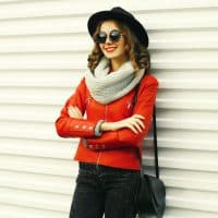 Portrait of beautiful young woman posing wearing a red jacket, black round hat on white background