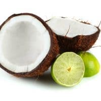 Split coconut and halved lime on white reflective background.