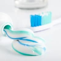 Toothbrush, tube of toothpaste and a glass on a white background