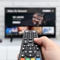 Man watching TV, remote control in hand. VOD service on TV