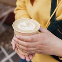 Bio paper cup with coffee in woman hand. Young stylish hipster redhead girl drinking hot latte. Urban lifestyle banner. Take away delivery concept. Eco recycle environment friendly.