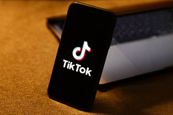 TikTok logo displayed on a phone screen and a laptop are seen in this illustration photo taken in Krakow, Poland on August 10, 2022. (Photo by Jakub Porzycki/NurPhoto via Getty Images)