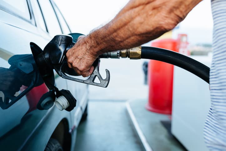 Close up senior man hands refueling his vehicle at gas station - Oil price increase concept